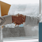 A business seller is in a handshake with a potential buyer as he finds the right buyer for the business.