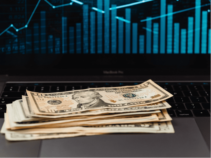 Stack of dollars on a laptop to depict maximizing the value of a small business. of a small business.