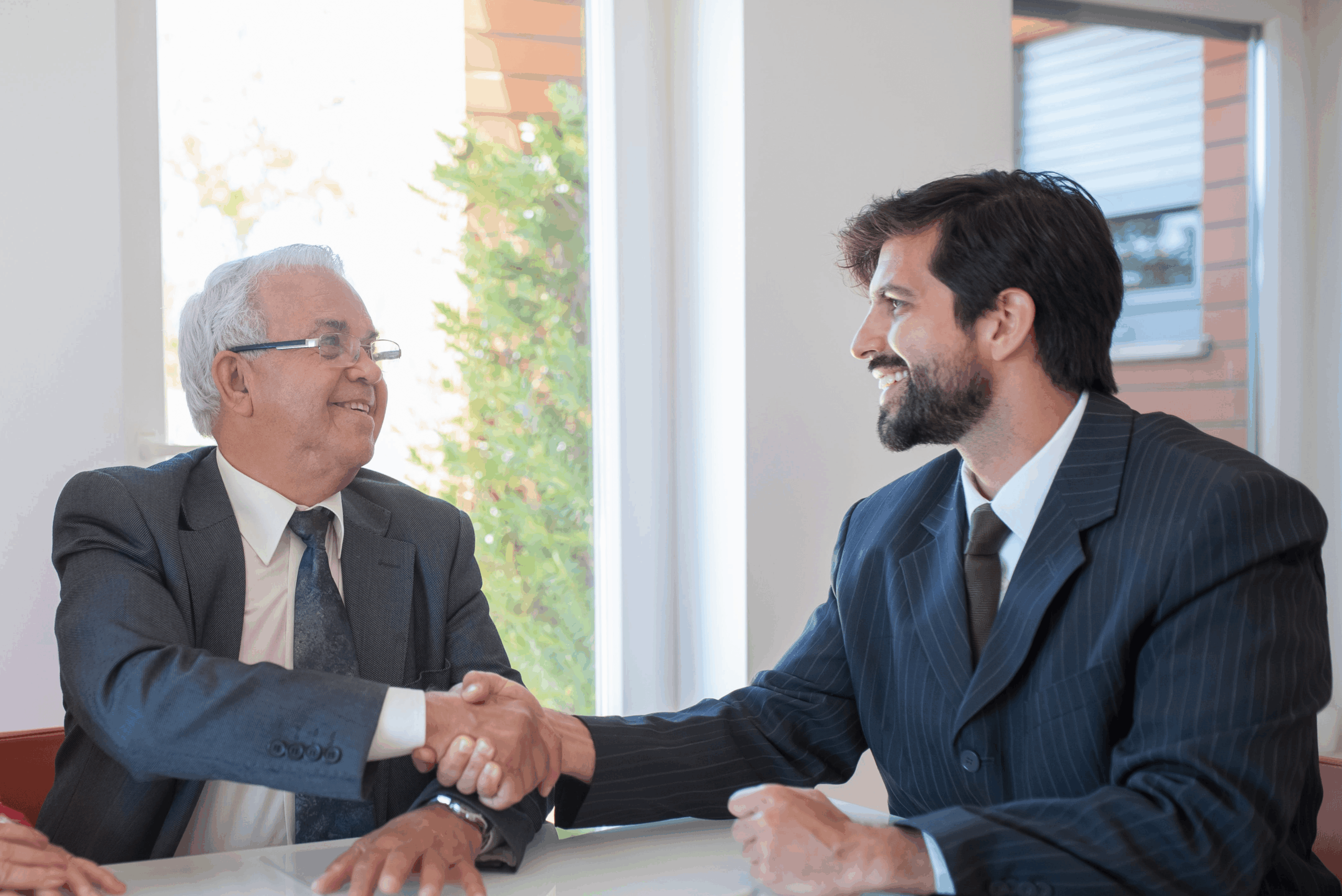 A business seller and buyer in a handshake as they successfully negotiate the sale of a business.